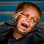 Little Boy Weeping With Hunger And Waiting For His Mother To Bring Food For Him